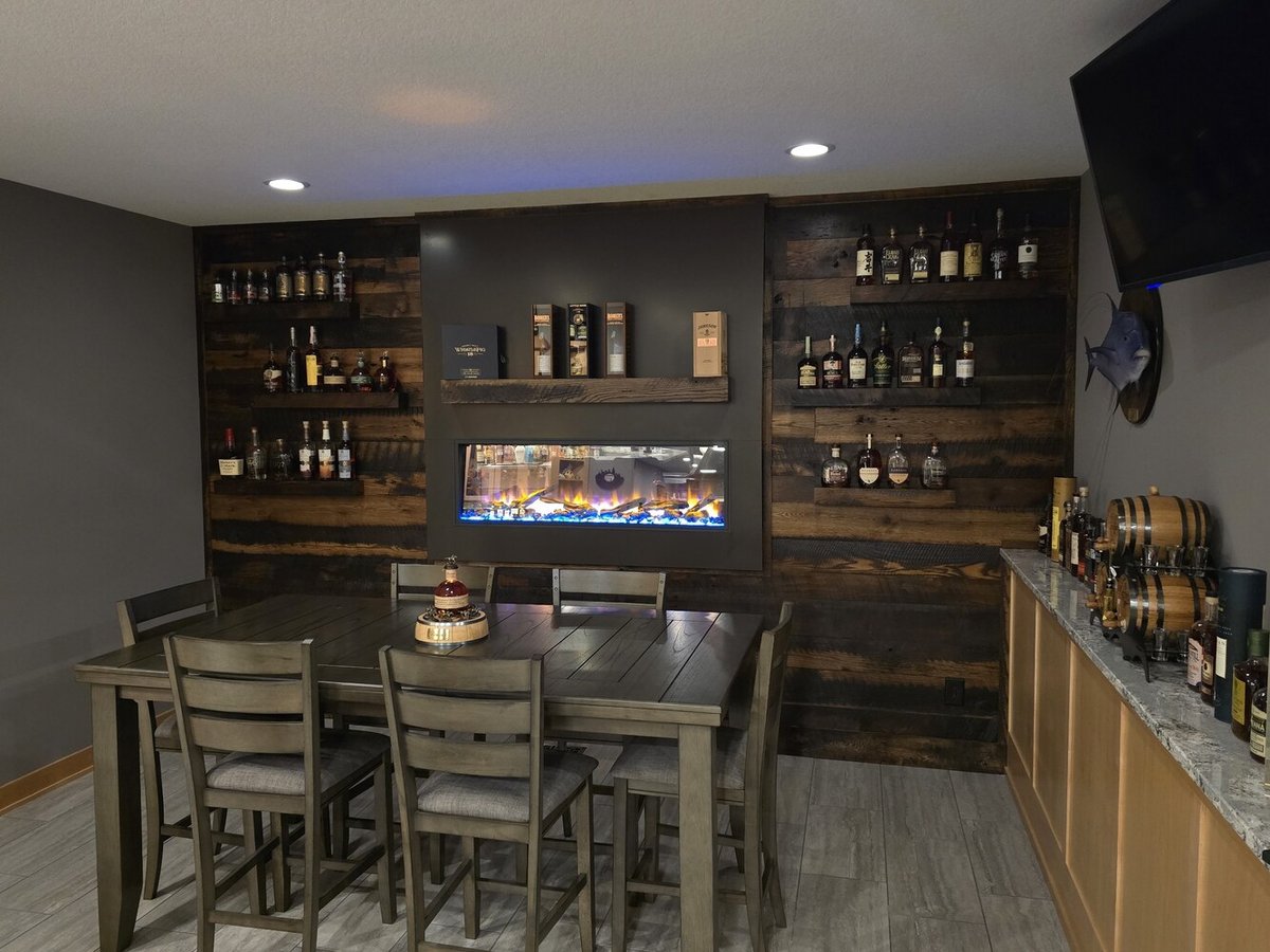 Basement bar and whiskey lounge with electric fireplace in a custom home in Ramsey, MN by Willet Remodeling and Construction.