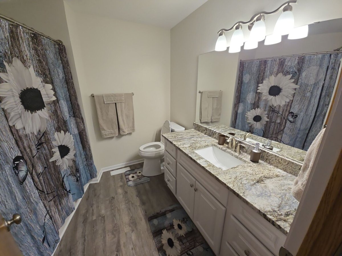 Full bathroom remodel with floral shower curtain in a Bethel, MN custom home by Willet Remodeling and Construction.