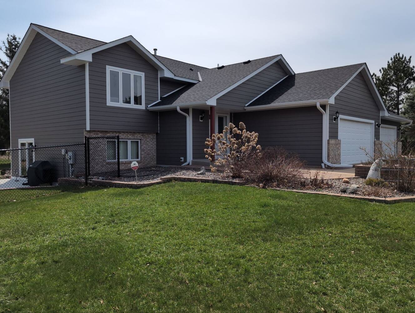 Side angle of remodeled gray home with white trim in Anoka, MN by Willet Remodeling and Construction.