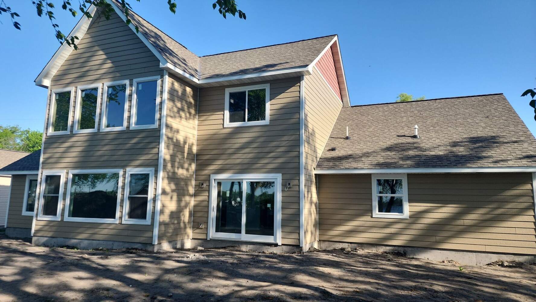 Two-story tan custom home with multiple windows in Saint Francis, MN by Willet Remodeling and Construction.