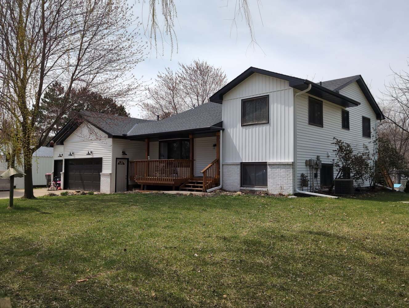 White and black remodeled home exterior with wood porch in Saint Francis, MN by Willet Remodeling and Construction.