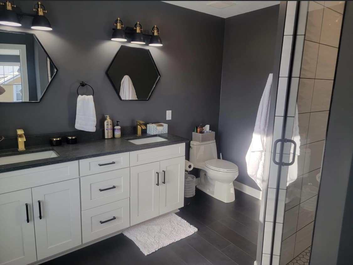 Dark-toned master bathroom with dual vanities and hex mirrors in a Ramsey, MN home by Willet Remodeling and Construction.