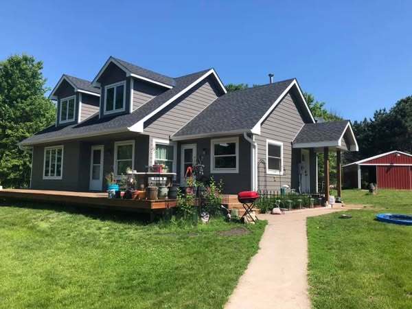 Gray two-story home with front porch and dormers in Saint Francis, MN by Willet Remodeling and Construction.