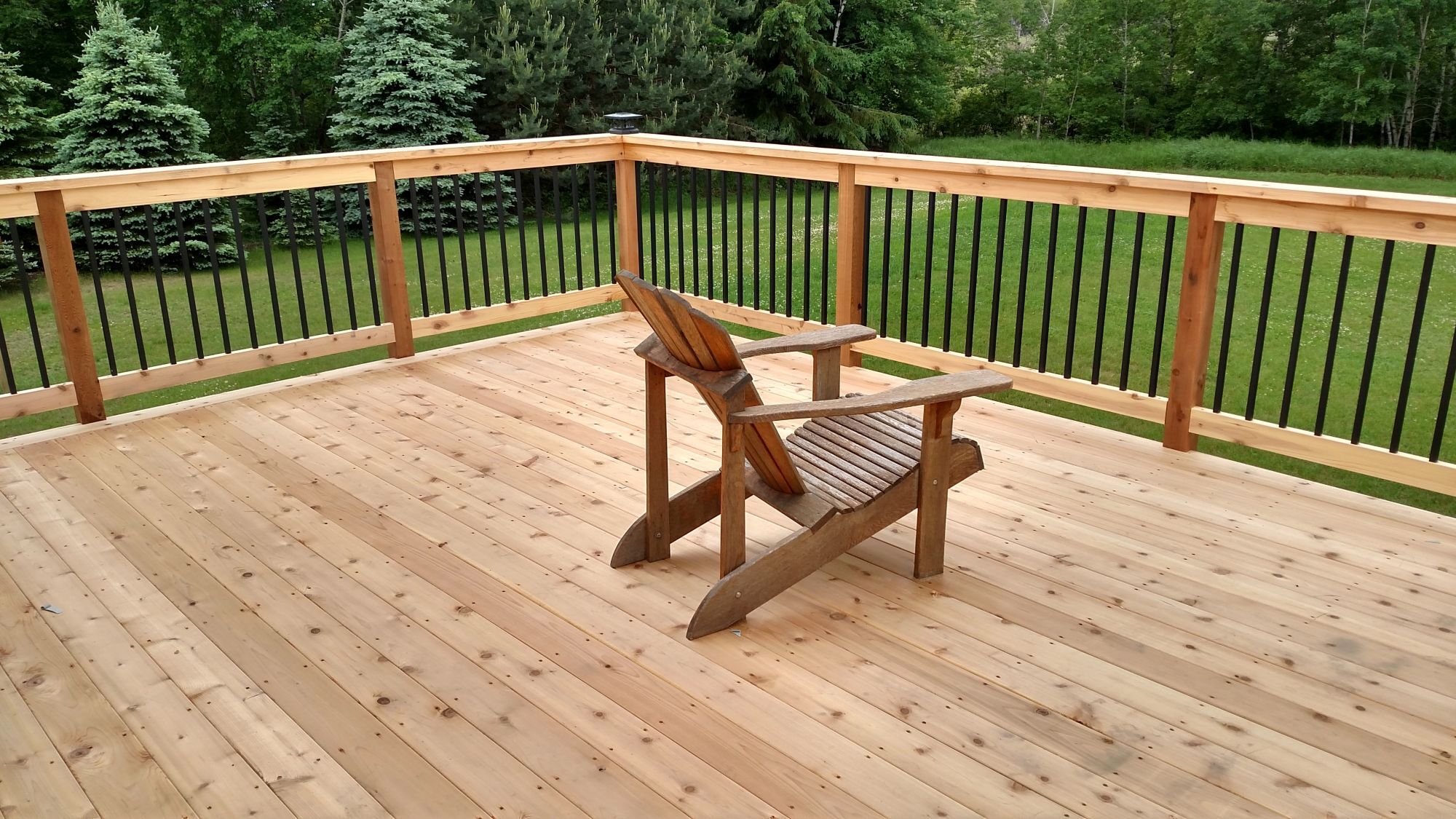 Cedar deck with black metal railings backyard by Willet Remodeling and Construction