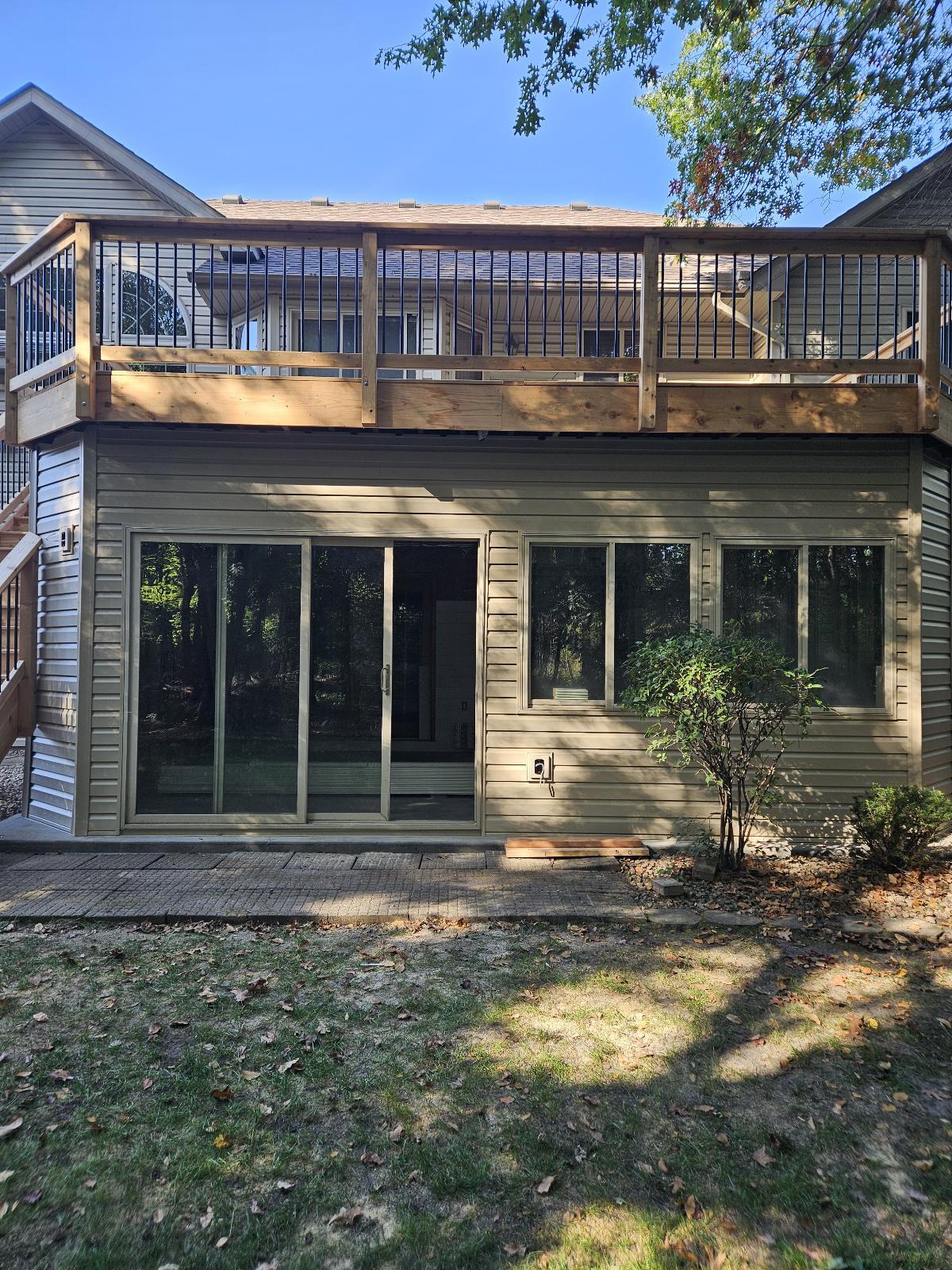 Rear home exterior with elevated wood deck and sliding patio doors